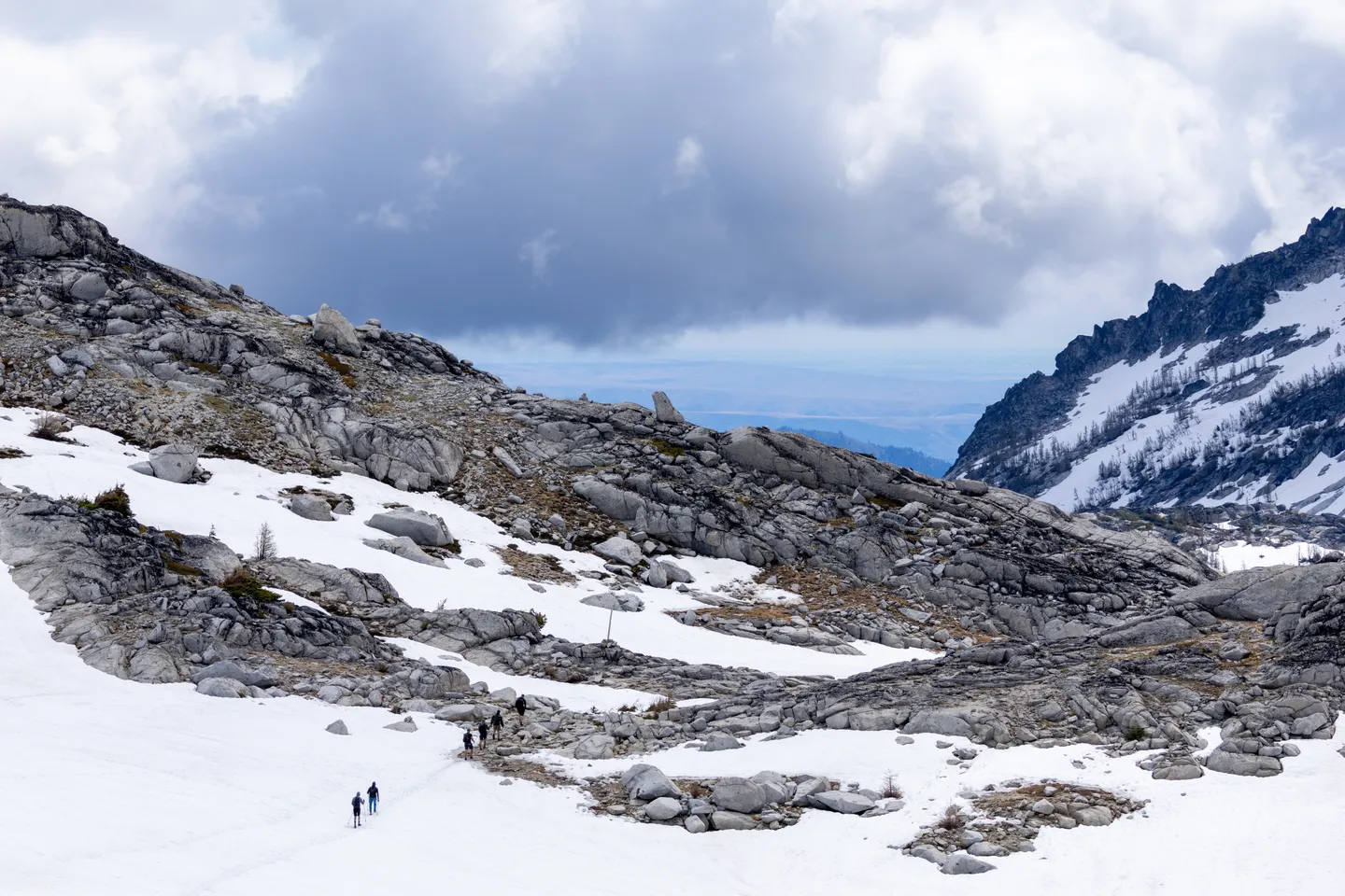 Hikers crossing a snow-filled alpine basin above Aasgard Pass.
