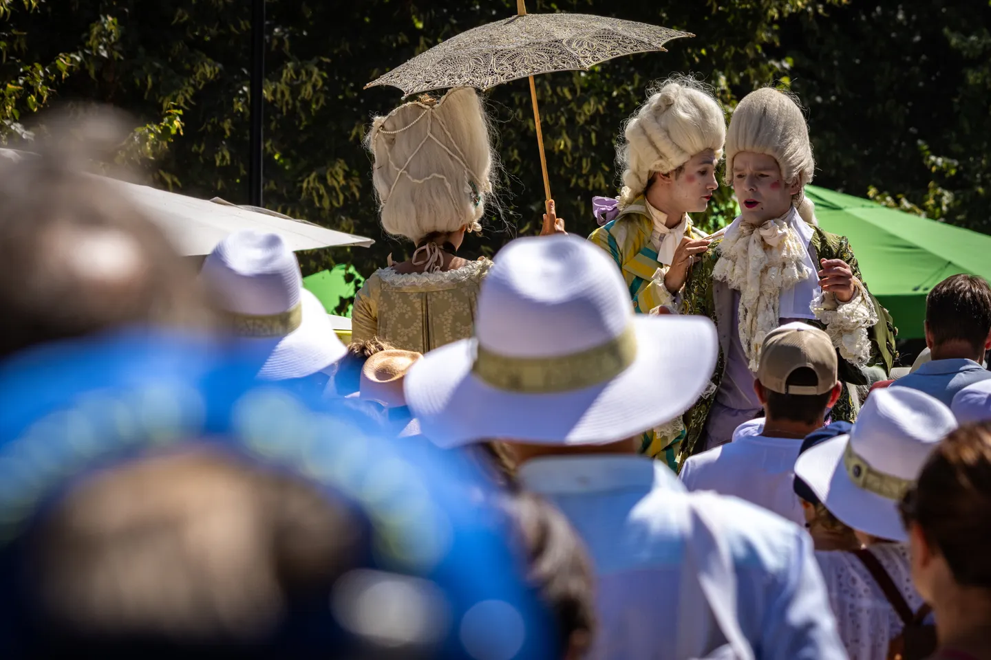 Costumed performers in 18th-century Versailles attire and powdered wigs.